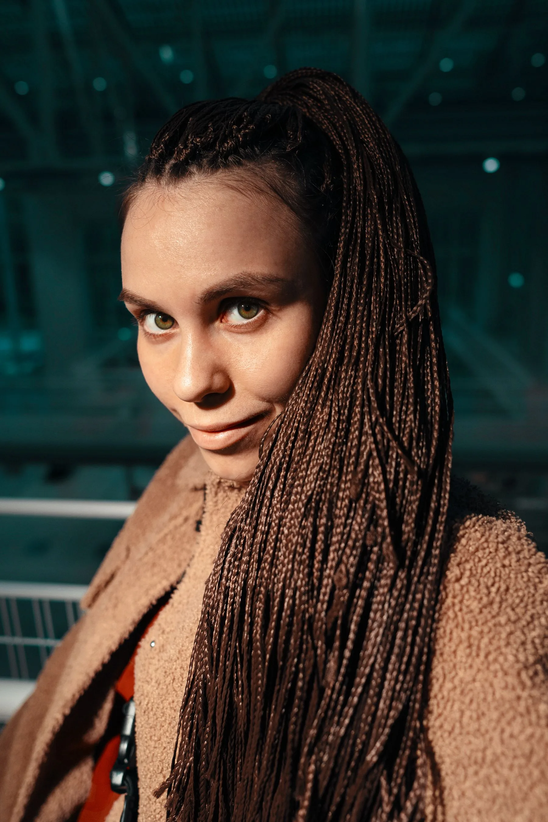 Woman with long braids smiling indoors